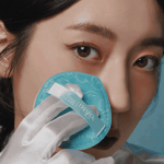 一位女子手中拿著藍色的粉撲放在臉上擺出將要化妝的姿勢
