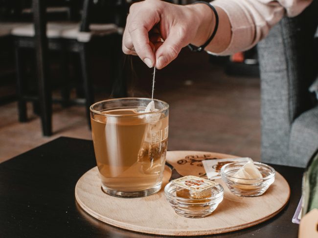 一隻手提出茶杯裡的茶包